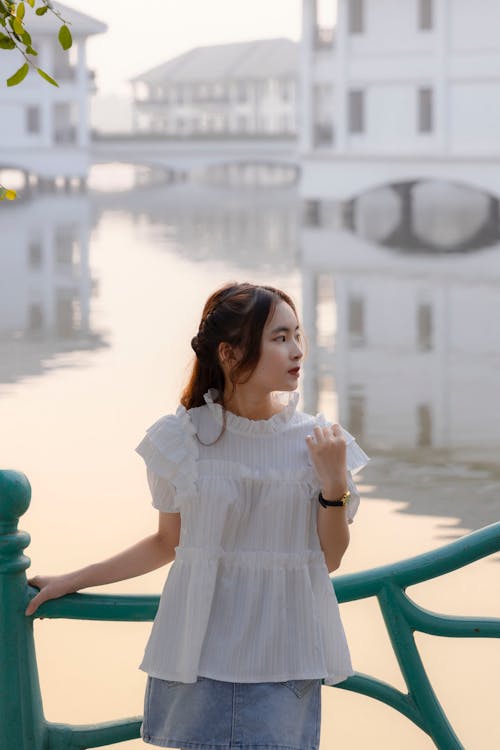 A woman standing on the bridge in front of a lake