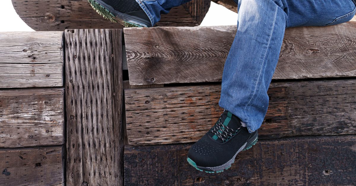 Casual jeans and sneakers resting on a rustic wooden bench, evoking a relaxed outdoor setting.