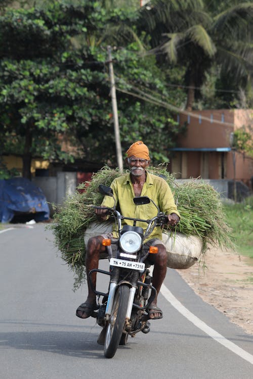 A man on a motorcycle carrying a load of hay