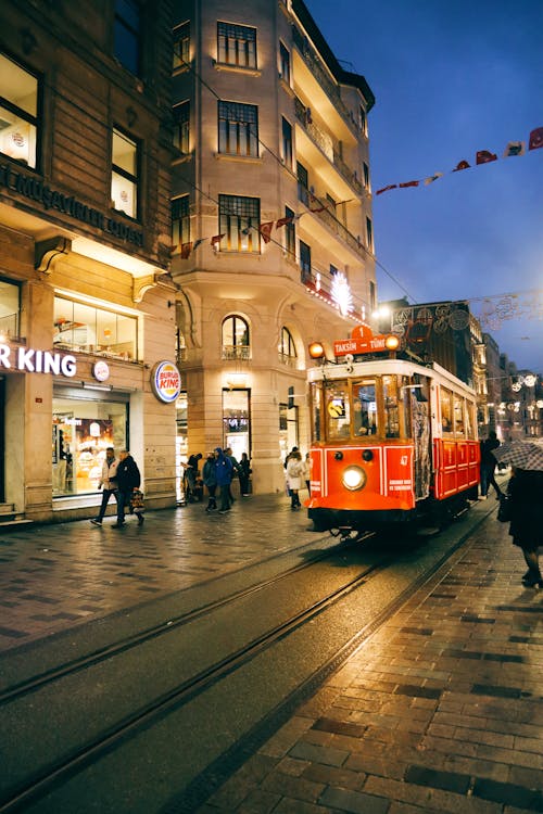 A red trolley on a street at night