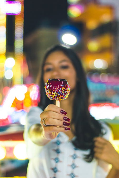 女人伸出糖果苹果的选择性焦点照片