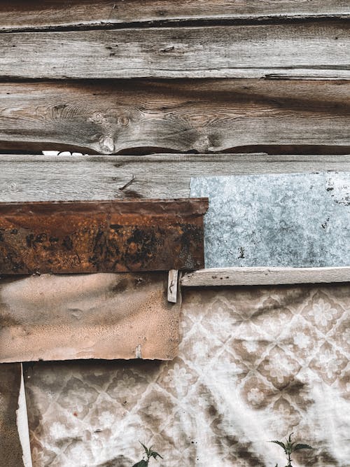 A rustic wooden wall with a piece of fabric and a metal plate