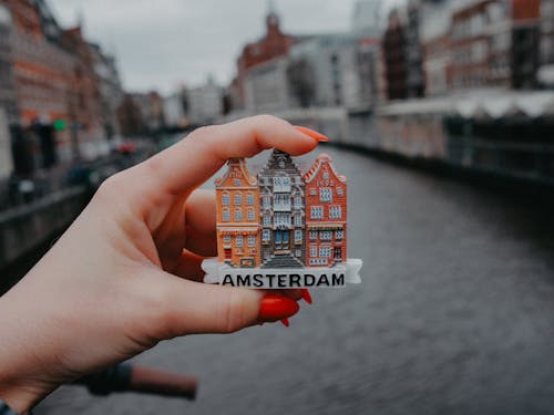 A person holding a small amsterdam building pin