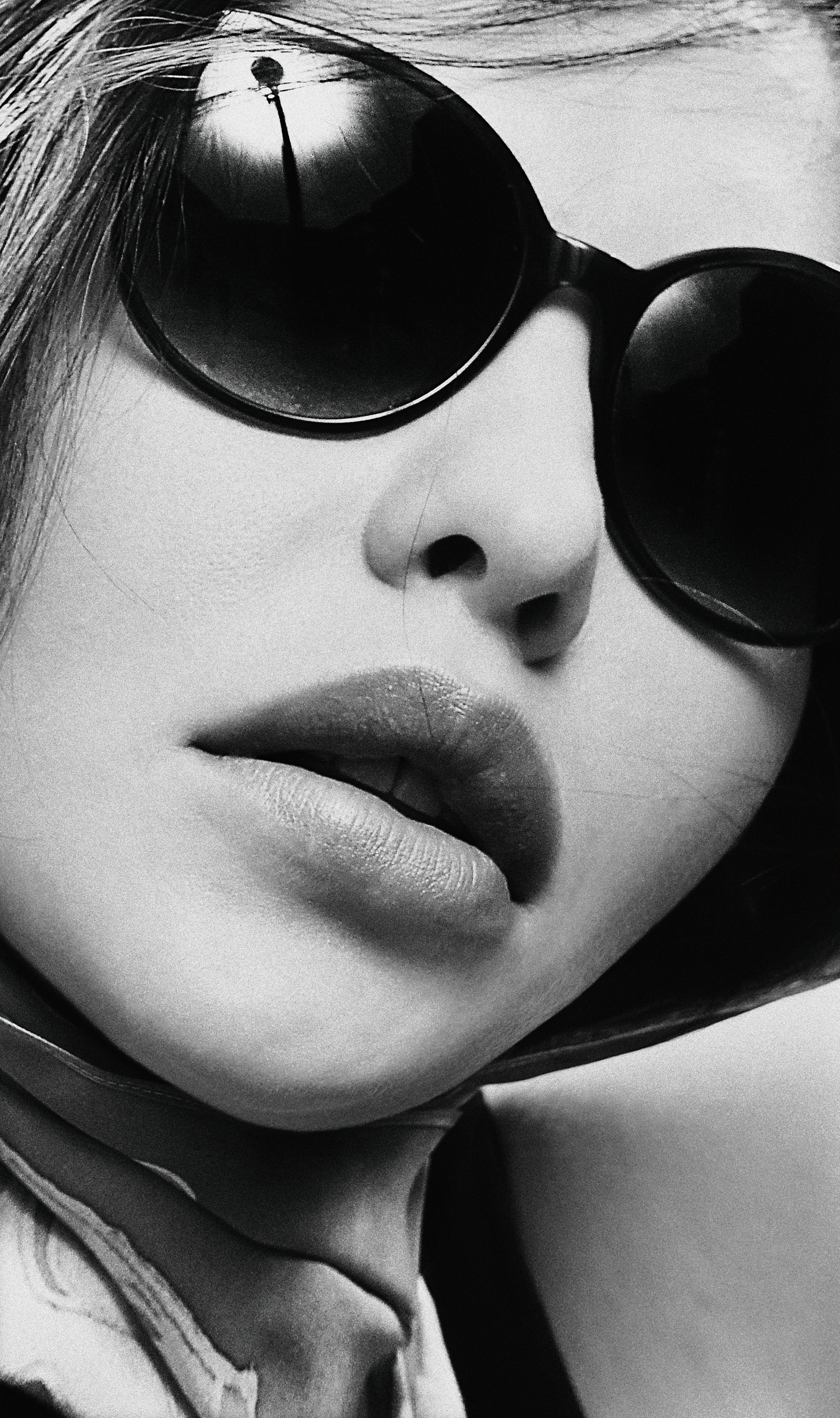 Striking black and white close-up of a young woman wearing sunglasses.