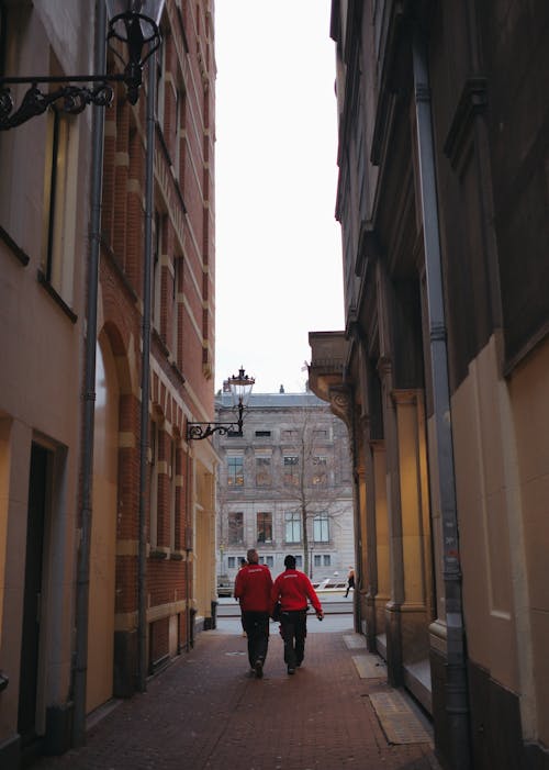 Two people walking down a narrow alleyway