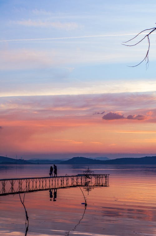 A couple standing on a dock at sunset