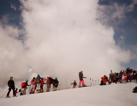 A vibrant scene of people enjoying a winter skiing adventure on a snowy mountain slope against a cloudy sky.