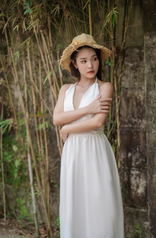 A woman in a white dress and straw hat