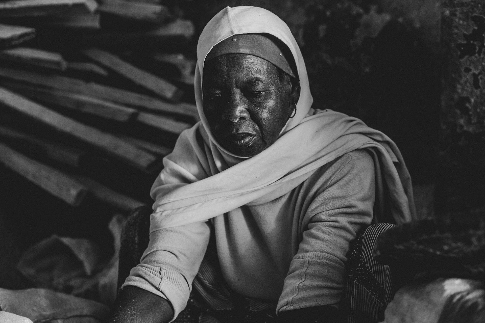 Elegant black and white portrait of a Nigerian woman sitting indoors, exuding grace and dignity.