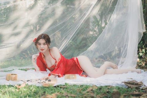 A woman in a red dress laying on the grass