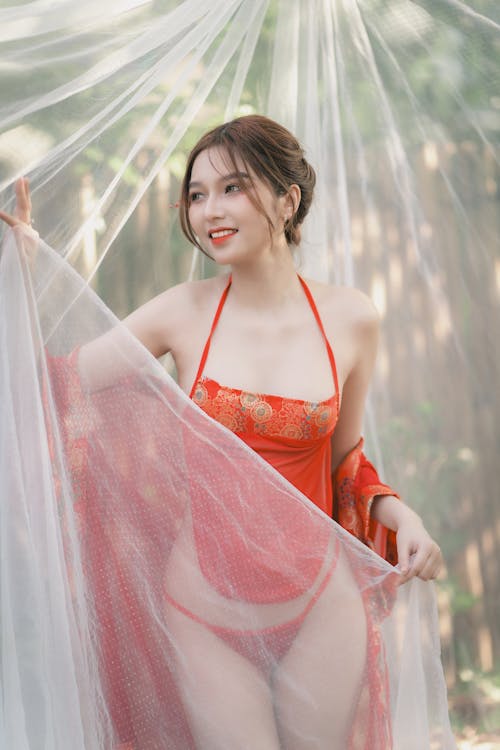 A woman in a red and white lingerie is posing