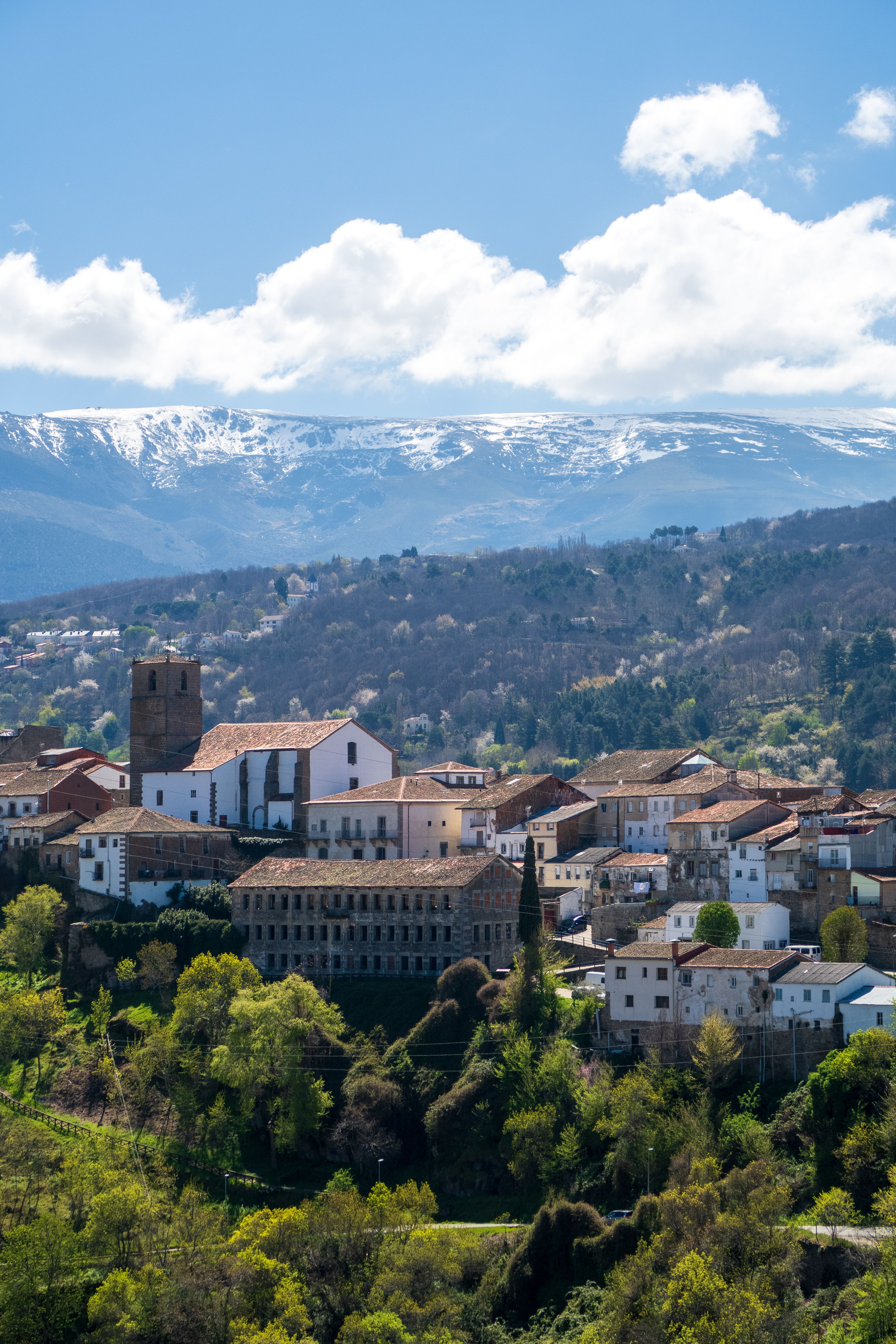 A scenic view of a quaint Spanish town with a mountainous backdrop and lush greenery.