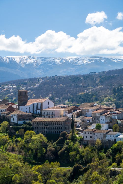 A town with a mountain in the background and snow capped mountains