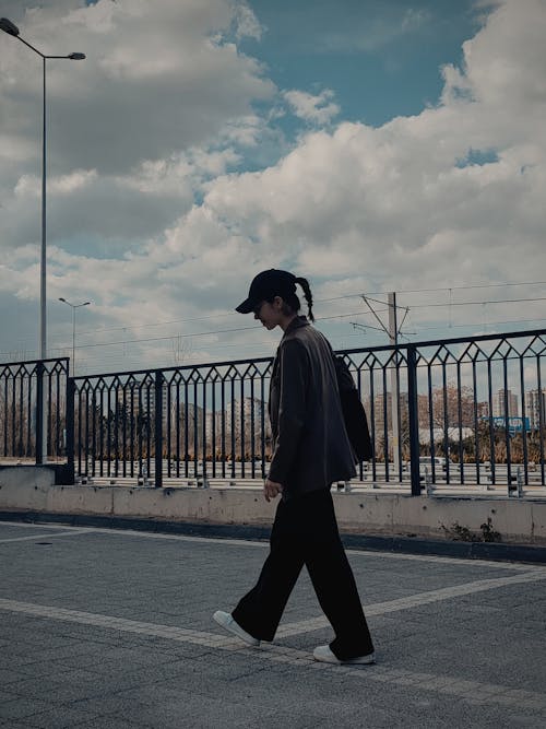 A man walking on a bridge with a hat