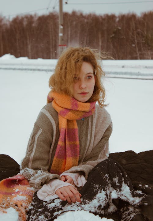 Young Woman Sitting on a Snowy Field