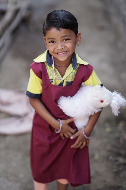 Free A cheerful Indian girl holding a stuffed toy, smiling outdoors in Nagpur, India. Stock Photo