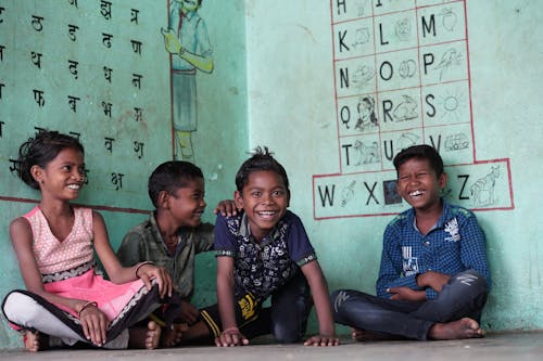Smiling Girl and Boys Sitting under Walls with Letters at School