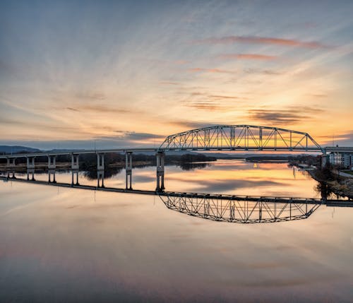A bridge over water at sunset with a reflection