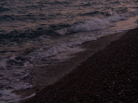 Gentle waves washing over the pebble beach during twilight, capturing the peaceful evening ambiance.