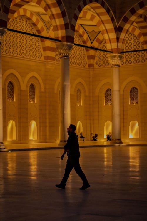 A man walking through an arched building at night