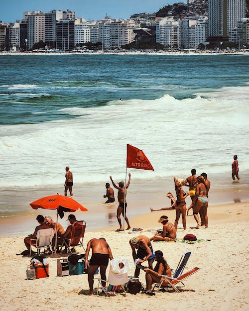 A group of people on the beach with a red flag