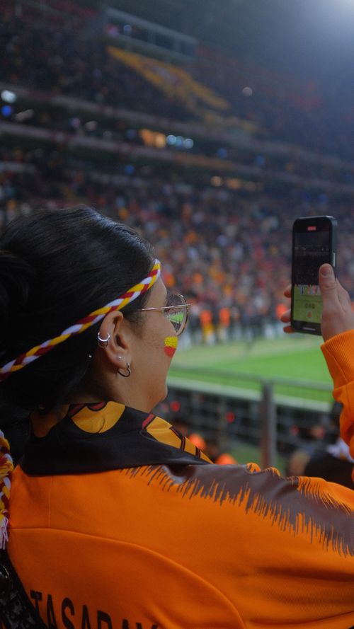 Free A woman records a live soccer match using her smartphone in a packed stadium. Stock Photo