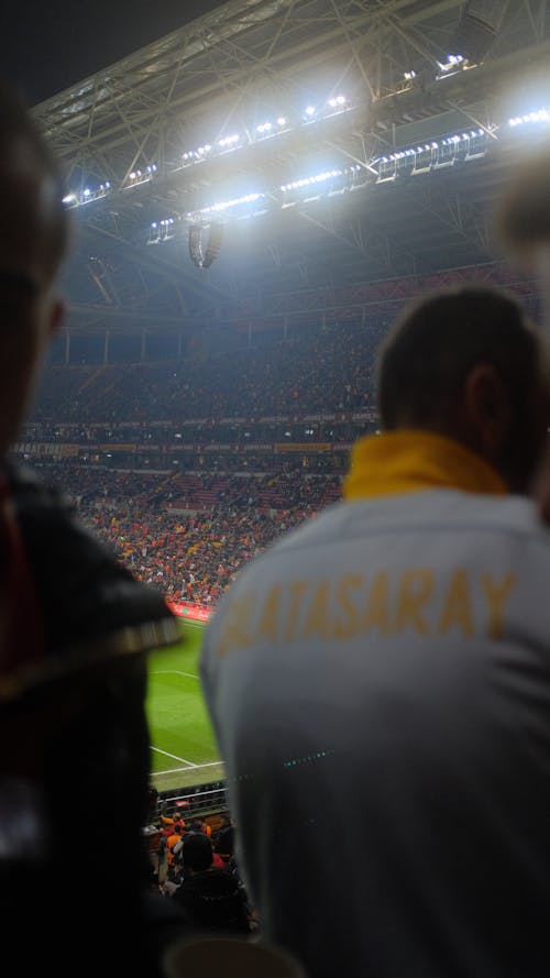 A man in a yellow shirt is standing in a stadium