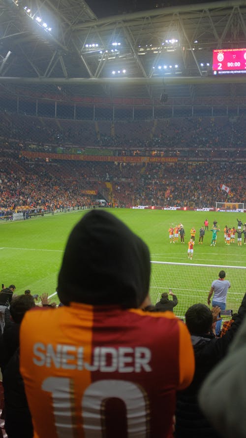 A soccer player is wearing a hoodie and is watching the game
