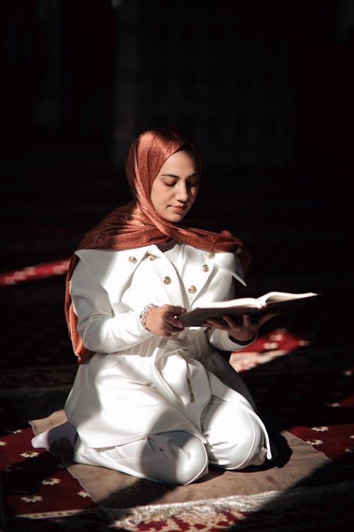 Free Woman Kneeling and Reading Koran Stock Photo