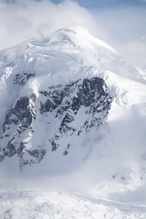 A snow covered mountain with a large snow covered peak