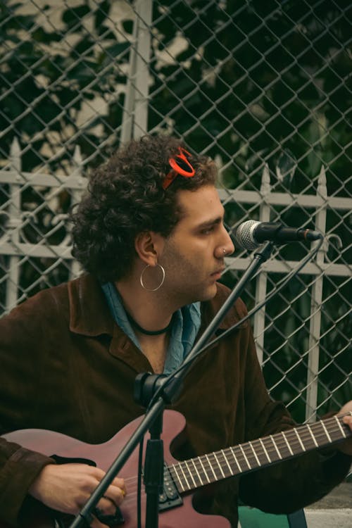 Man Playing a Guitar and Singing on a Street