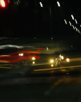 Blurred long exposure photo capturing vibrant city traffic lights at night on urban streets.