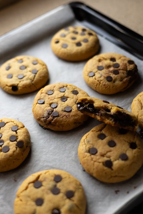 Chocolate chip cookies on a baking sheet with a bite taken out of one