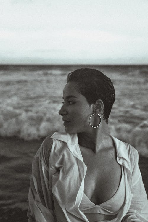 A woman in white shirt and earrings standing on the beach