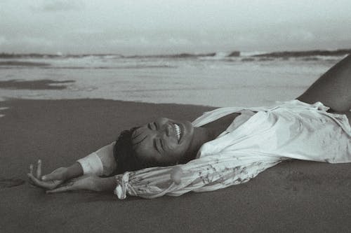 A woman laying on the beach with her arms out