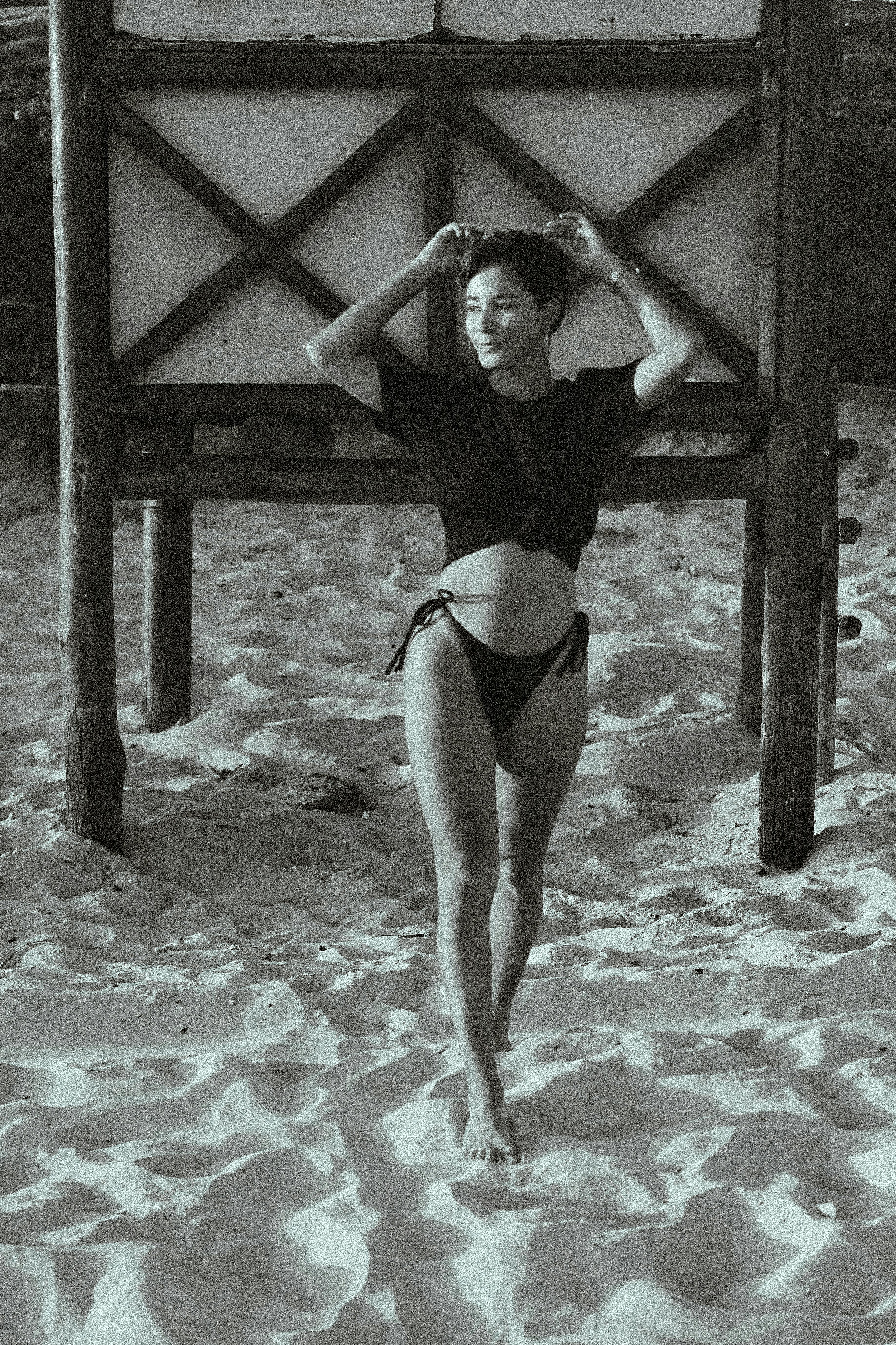Stunning black and white photo of a woman enjoying the sun on a sandy beach.