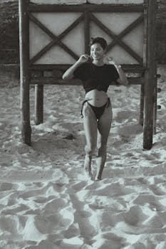 Woman smiling in swimsuit at the beach, showcasing summer fun and leisure.