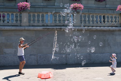 A man and a child playing with bubbles in the street