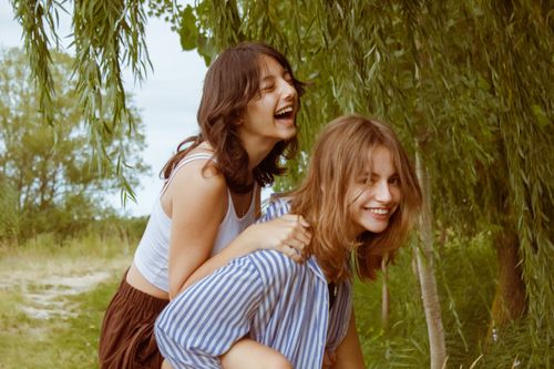 Free Two young adults share a joyful moment in a lush green forest, evoking happiness and friendship. Stock Photo