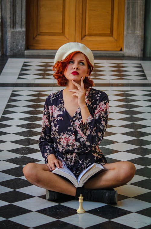 A woman sitting on a checkered floor with a book