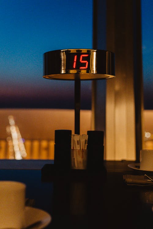 A clock on a table with a view of the city