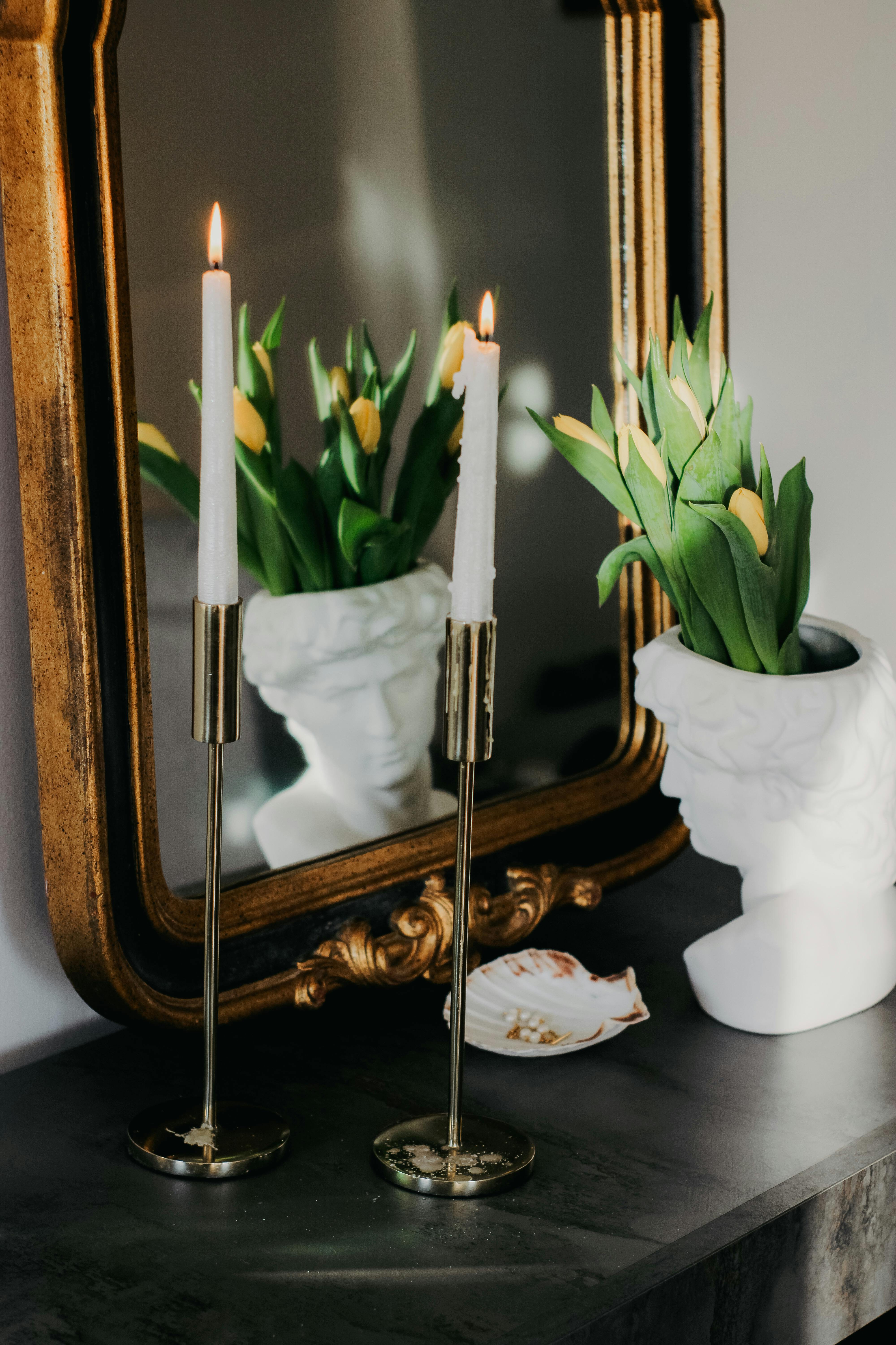 Chic arrangement of candles, a flowerpot, and a mirror for stylish interiors.