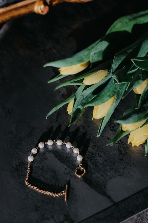 A bracelet with pearls and tulips on a table