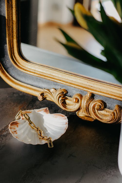 A gold mirror and shell on a table