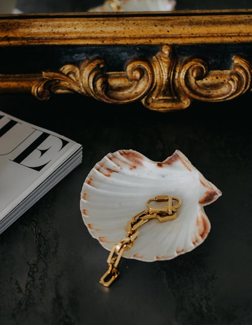 A gold chain and shell on a table