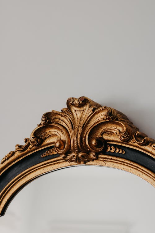 A gold mirror with black trim and a gold frame