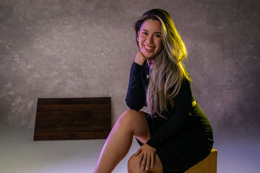 Fashion portrait of a smiling woman in a black dress with blonde hair, captured in a studio setting.