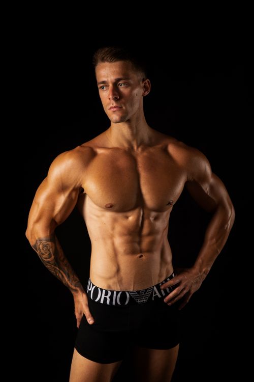 Free Muscular man with tattoos posing topless in studio against black background Stock Photo