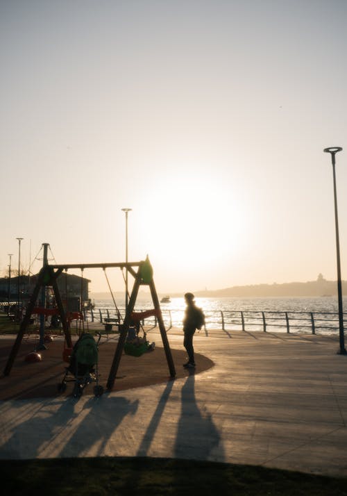 A person walking on a playground at sunset