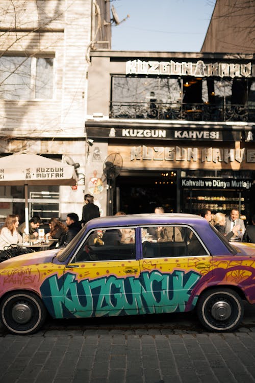 A car with graffiti on it parked in front of a restaurant